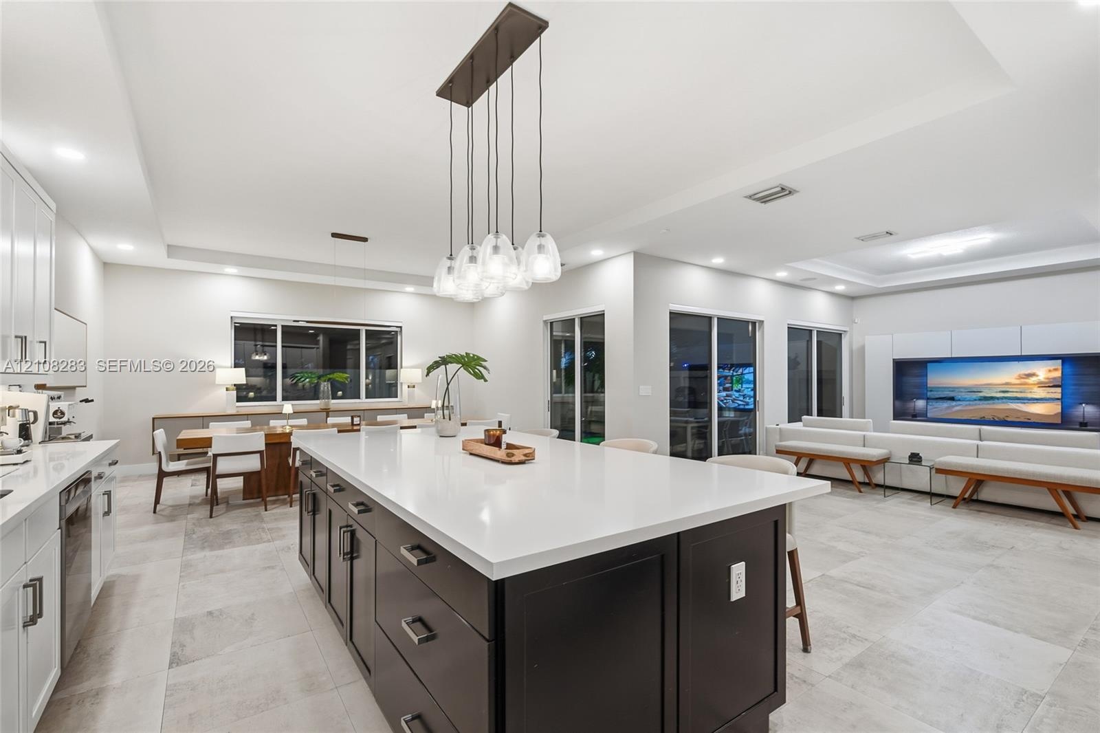 Kitchen featuring a center island with contrasting cabinetry, stone-finish countertops, tile flooring, built-in media console, and multi-pendant light