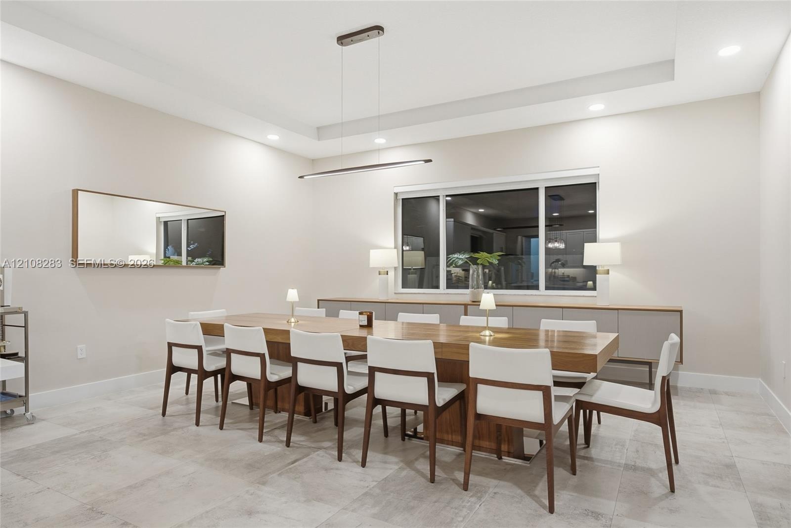 Tray ceiling with recessed lighting, linear pendant fixture, large-format tile flooring, and built-in cabinetry featuring a smooth countertop