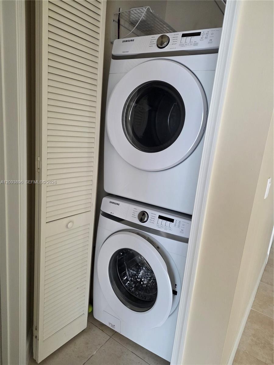 Stacked front-load washer and dryer set, white louvered bifold door, and built-in overhead wire shelving