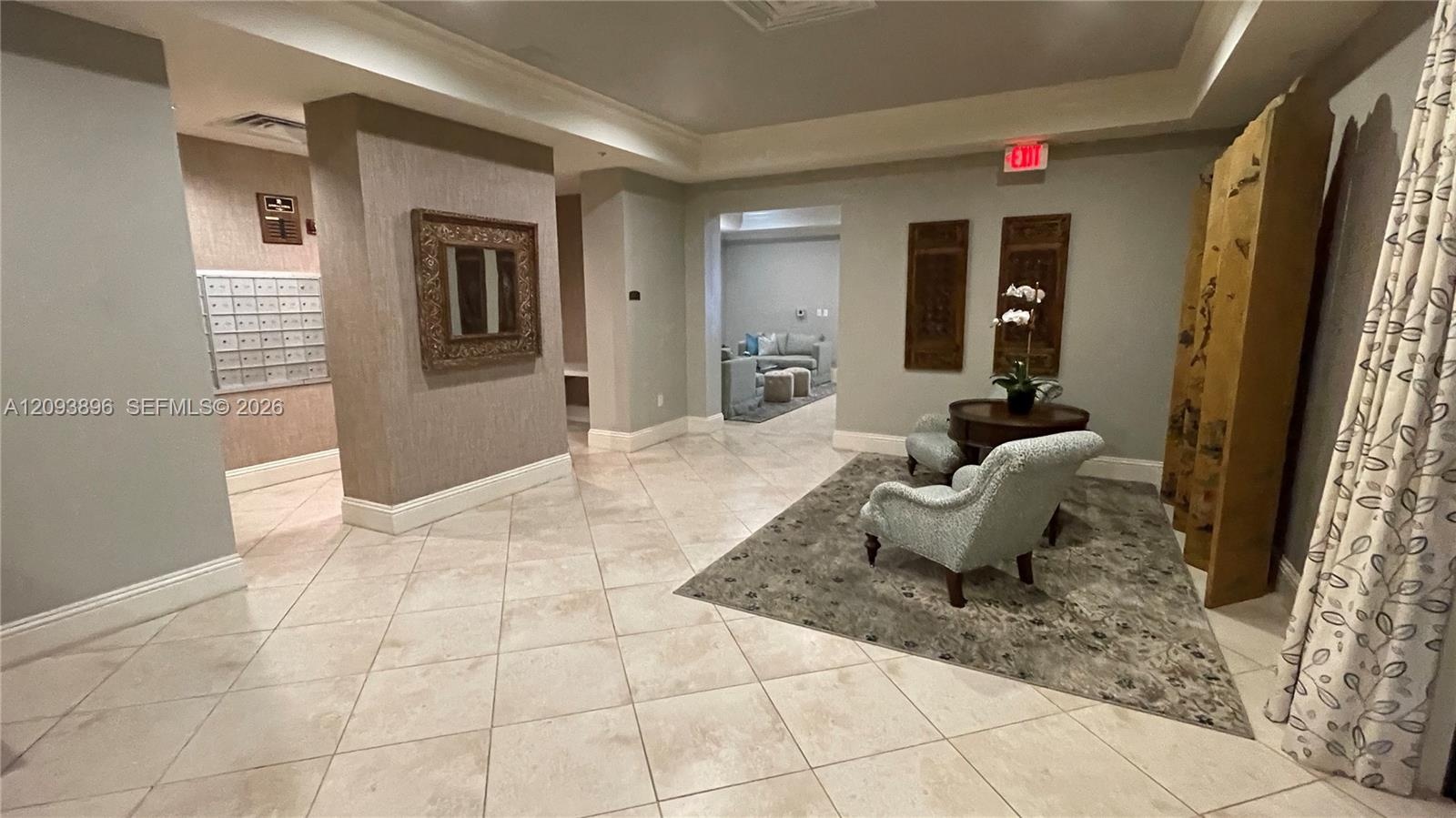 Lobby area featuring large-format tile flooring, a recessed tray ceiling, and built-in metal postal boxes