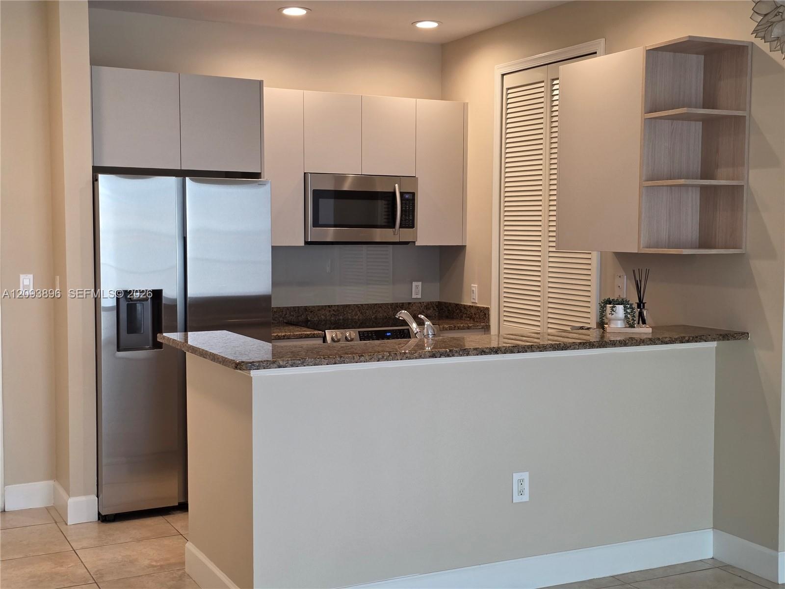 Kitchen featuring flat-panel cabinetry, stone countertops, stainless steel appliances, built-in microwave, and open shelving