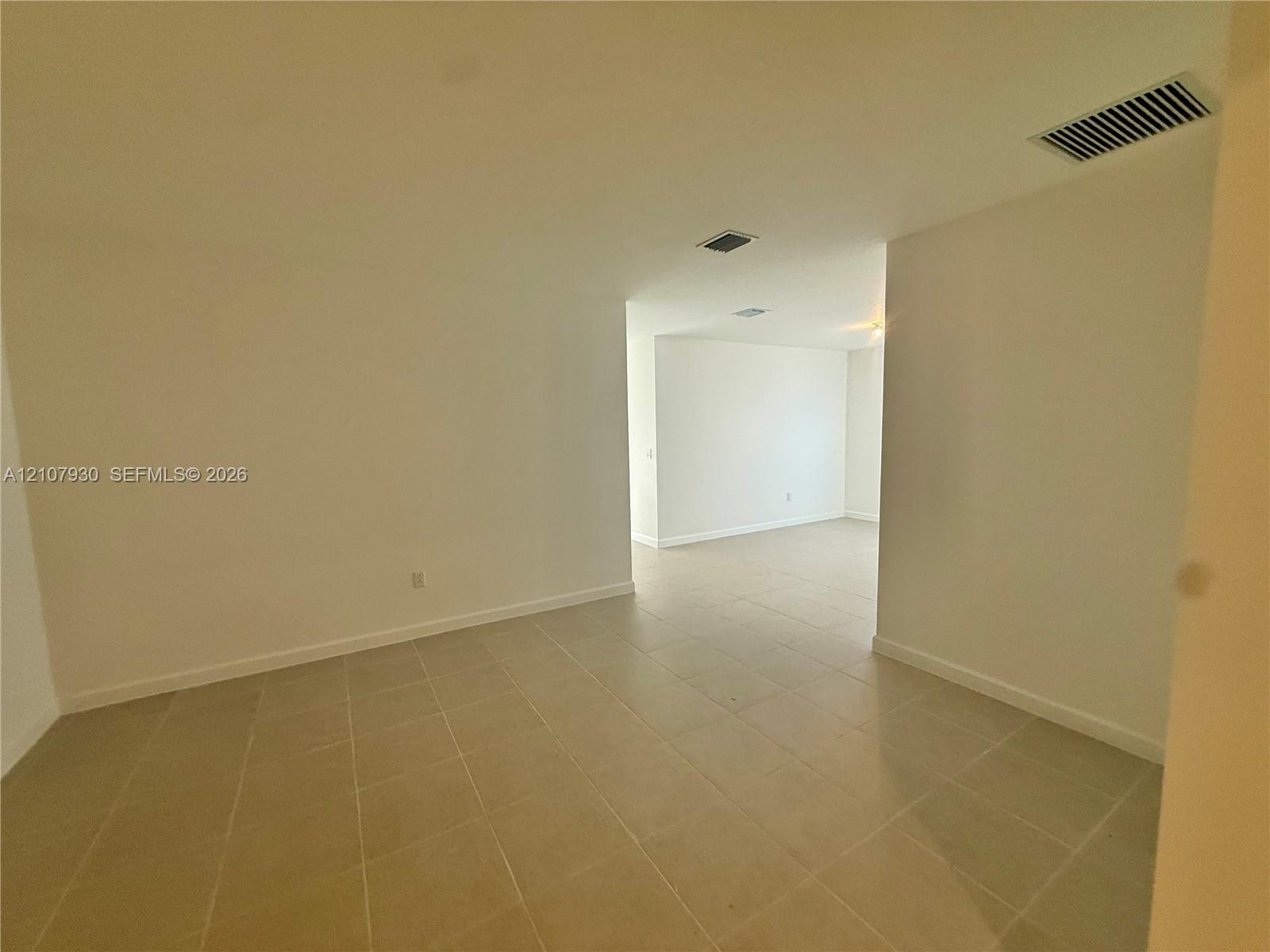 Neutral-toned ceramic tile flooring throughout the interior, complemented by smooth walls and high ceilings