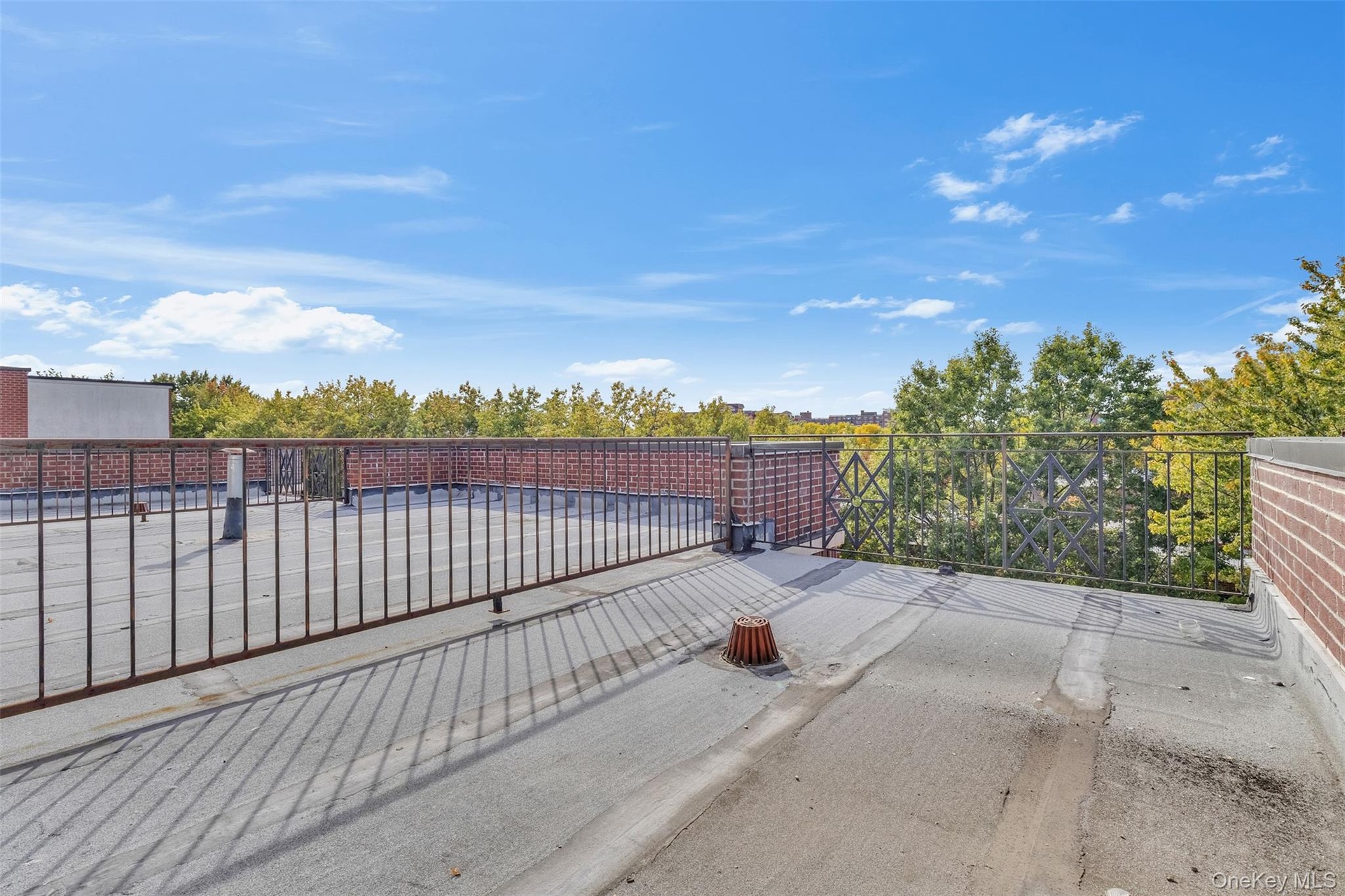 Rooftop terrace featuring a flat surface, low-profile brick parapet walls, and black metal perimeter railings