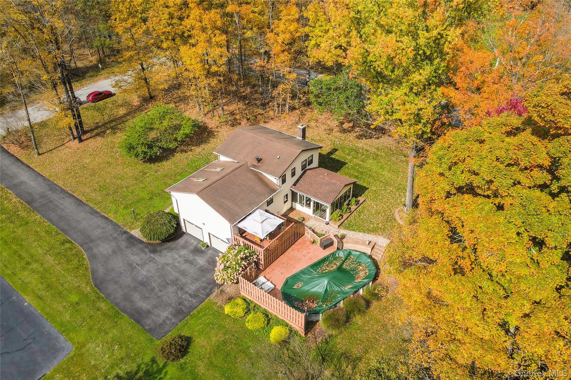 Expansive backyard with a manicured lawn and mature trees,  above ground pool and featuring a multi-level wood deck and a stone chimney