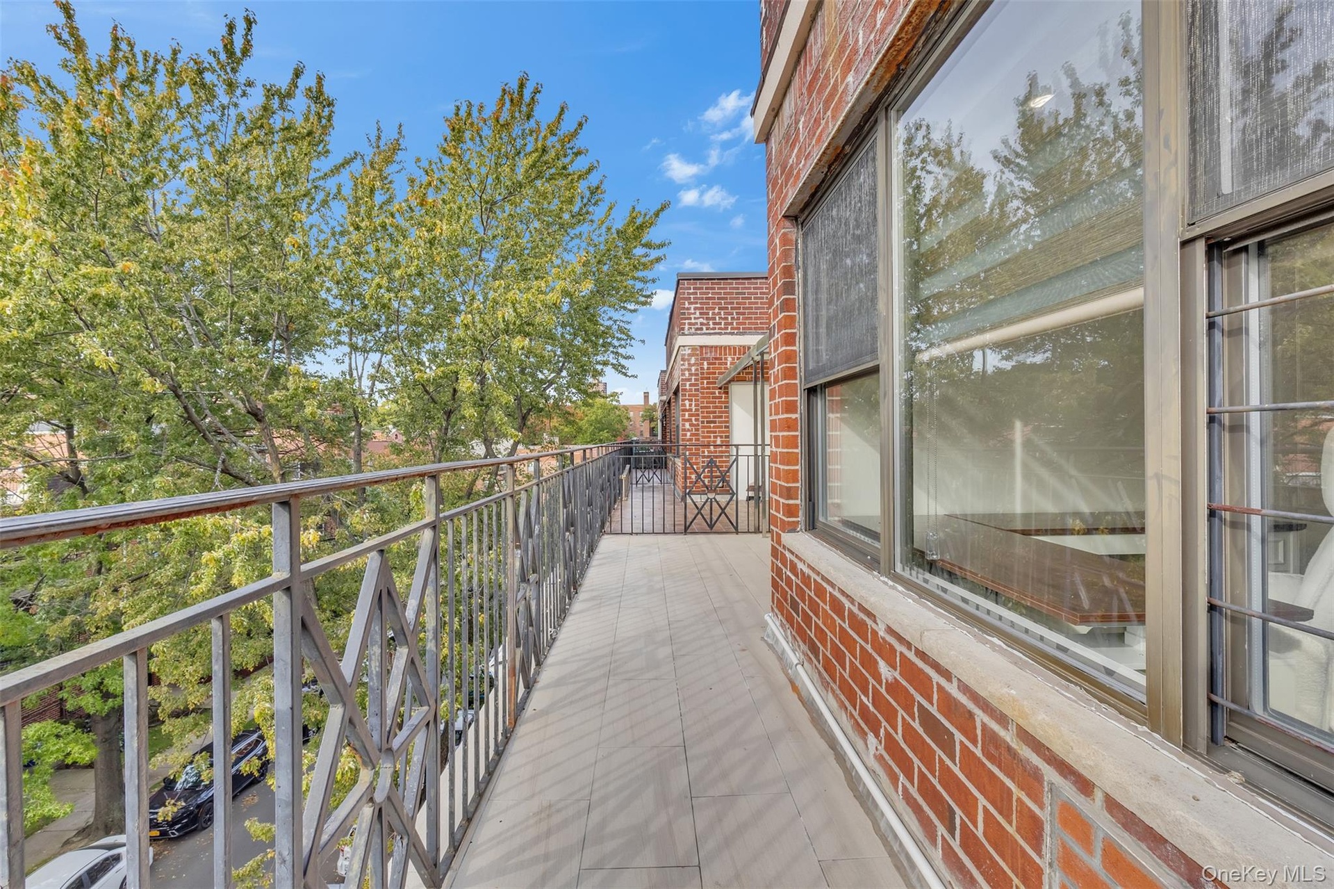 Exterior balcony featuring brick masonry walls, tiled flooring, and decorative metal railings