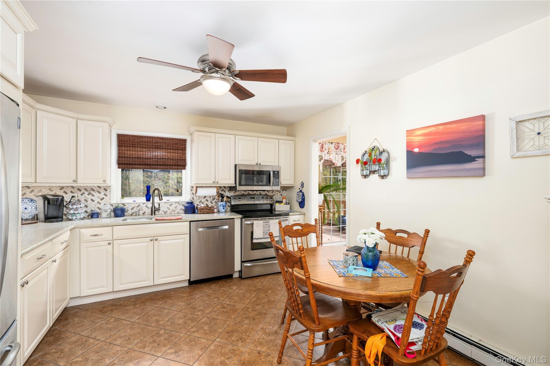 Kitchen featuring white cabinetry, stainless steel appliances,  quartz counters, a herringbone-pattern tile backsplash, and a central ceiling fan with