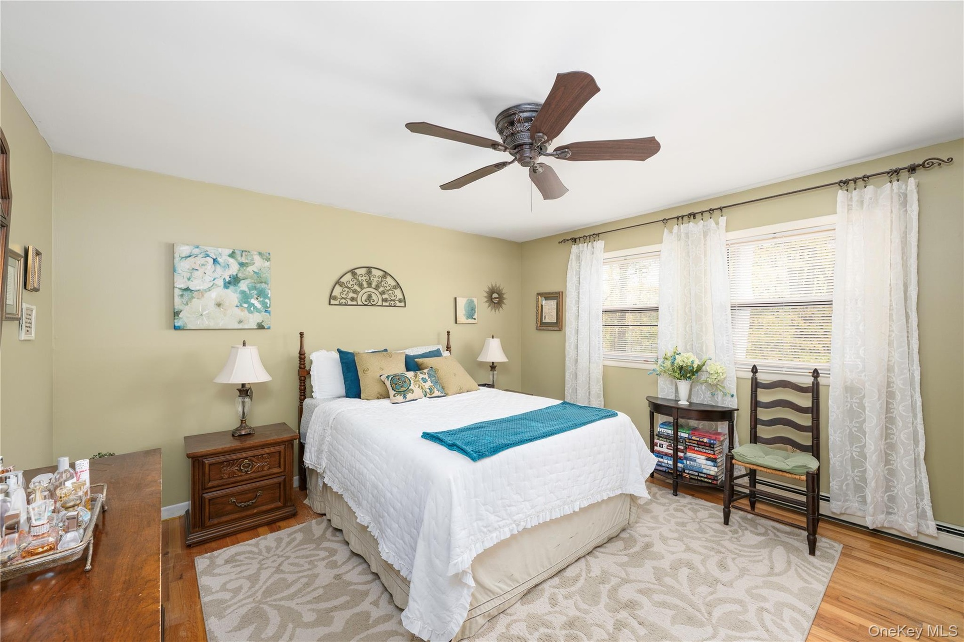 Bedroom featuring hardwood flooring, primary bathroom, walk in closet with access to attic, ceiling fan