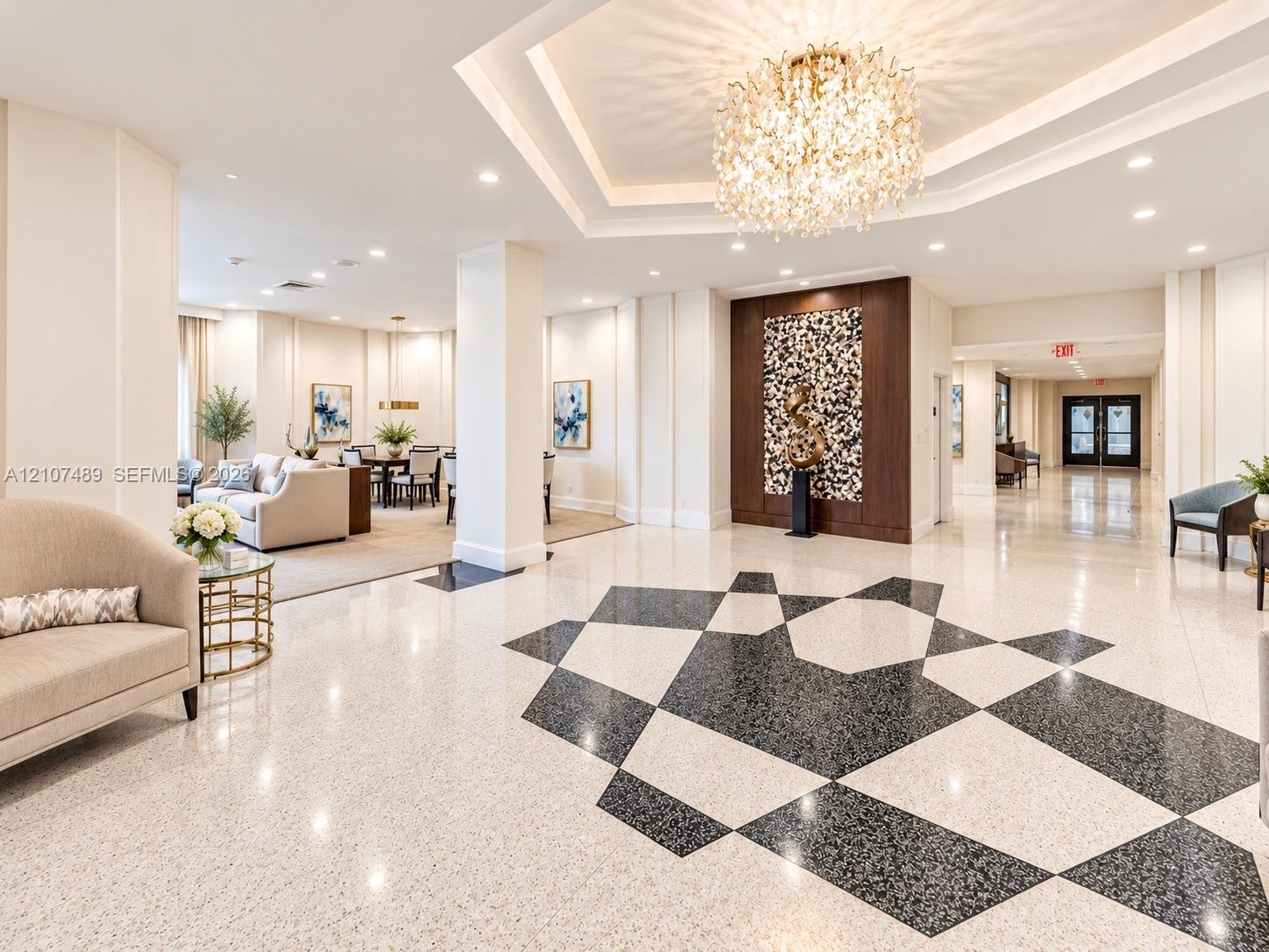 Grand lobby featuring geometric patterned terrazzo flooring, a coffered tray ceiling, a central crystal chandelier, and a decorative wood-paneled acce