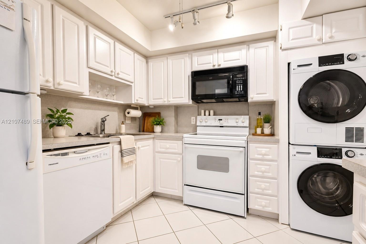 Kitchen featuring white cabinetry, solid-surface countertops, tile flooring, track lighting, and a built-in laundry unit