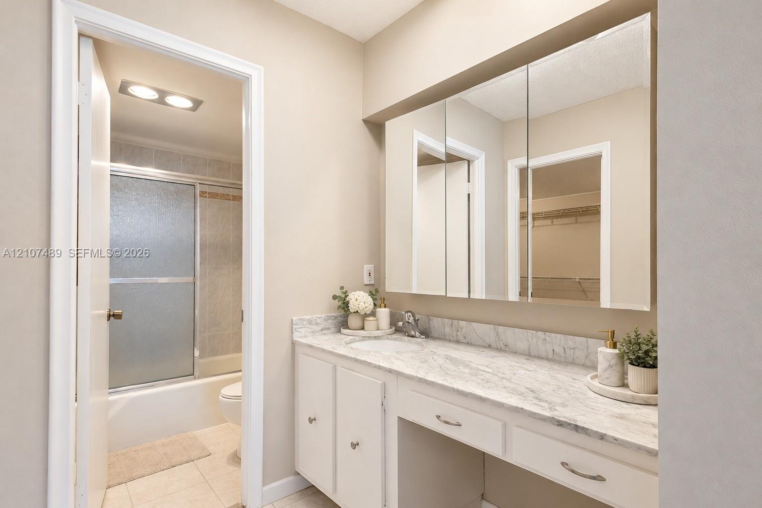 Vanity featuring a stone-look countertop, integrated sink, built-in medicine cabinet, and a dedicated seated vanity space, complete with a separate ar