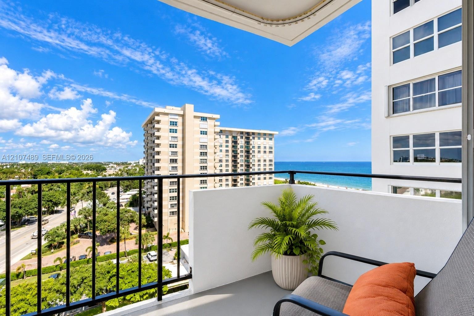 Private balcony featuring black metal railings, solid partition walls, and expansive ocean and coastal scenery
