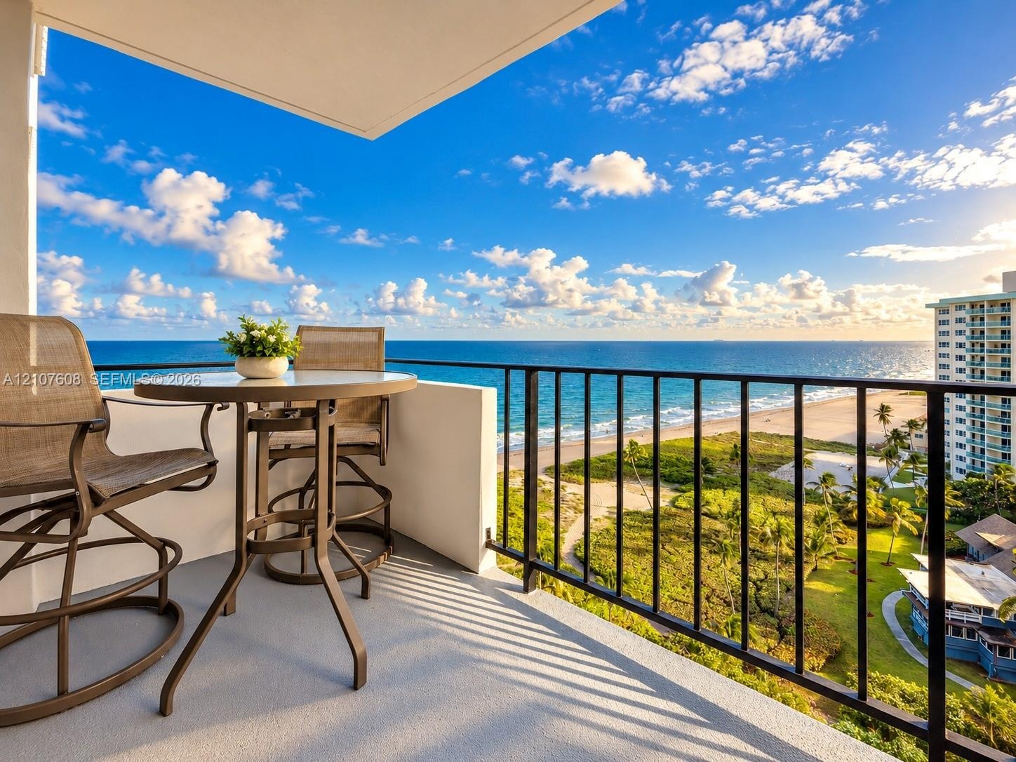 Private balcony featuring a concrete floor, solid masonry wall, and black metal railing, showcasing direct oceanfront scenery
