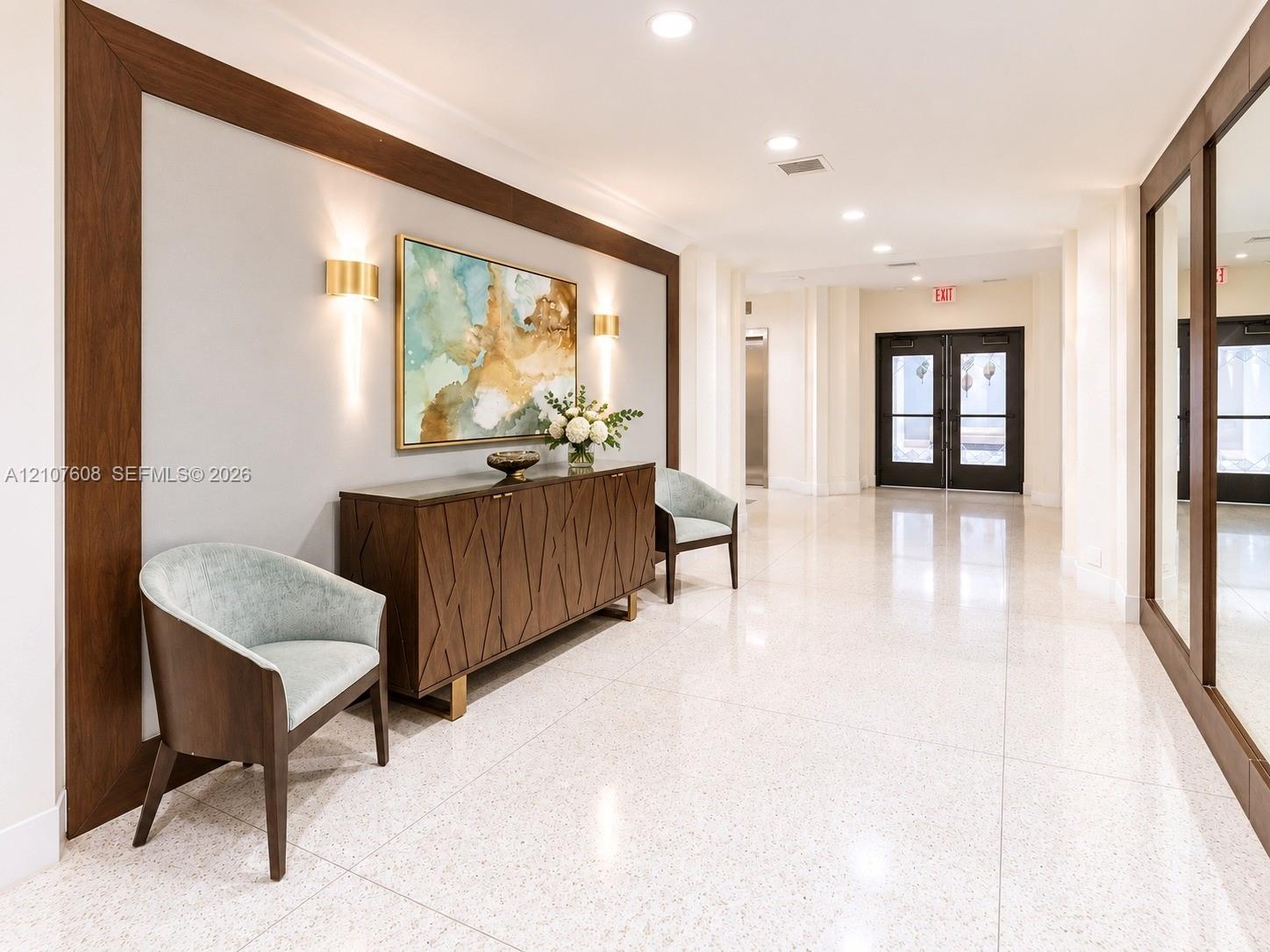 Polished stone flooring, wood-framed wall detailing, recessed ceiling lighting, and brass-finish wall-mounted sconces