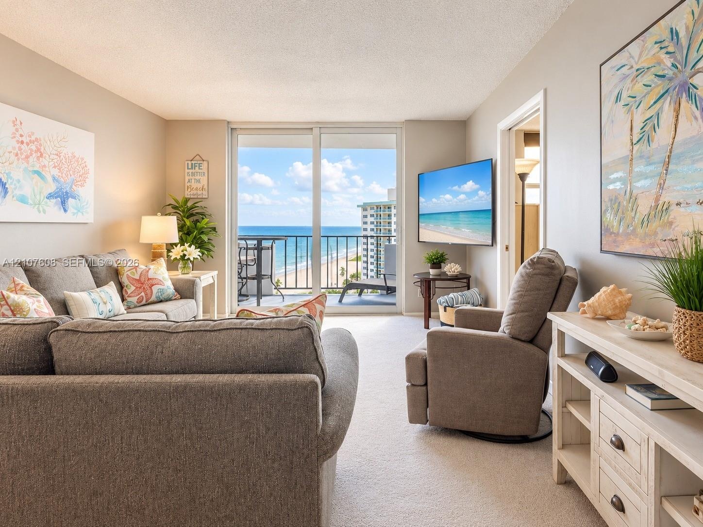 Living area featuring full-height sliding glass doors leading to a private balcony with ocean frontage