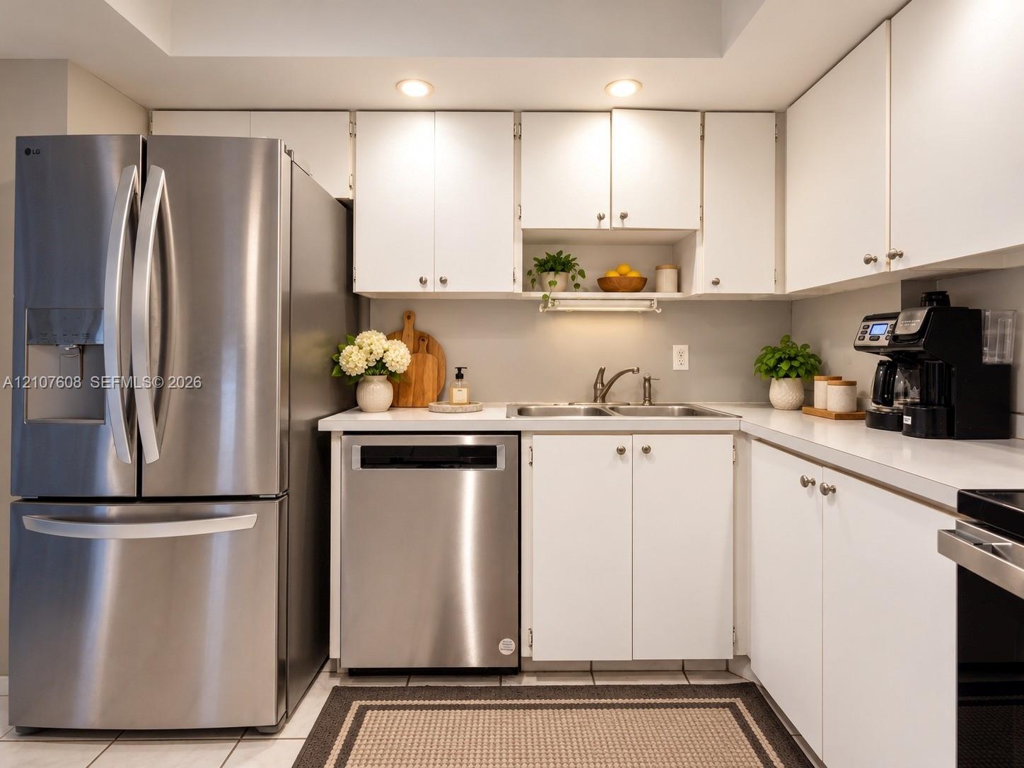 Kitchen featuring white cabinetry, stainless steel French door refrigerator, stainless steel dishwasher, solid-surface countertops, and recessed light