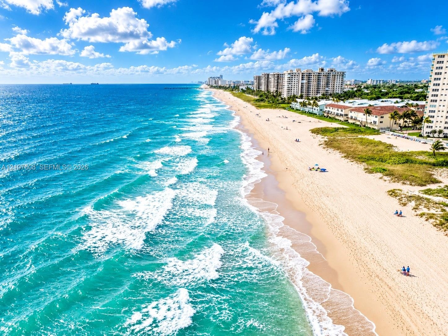 Coastal aerial perspective featuring sandy shoreline, turquoise ocean waters, and direct beach access