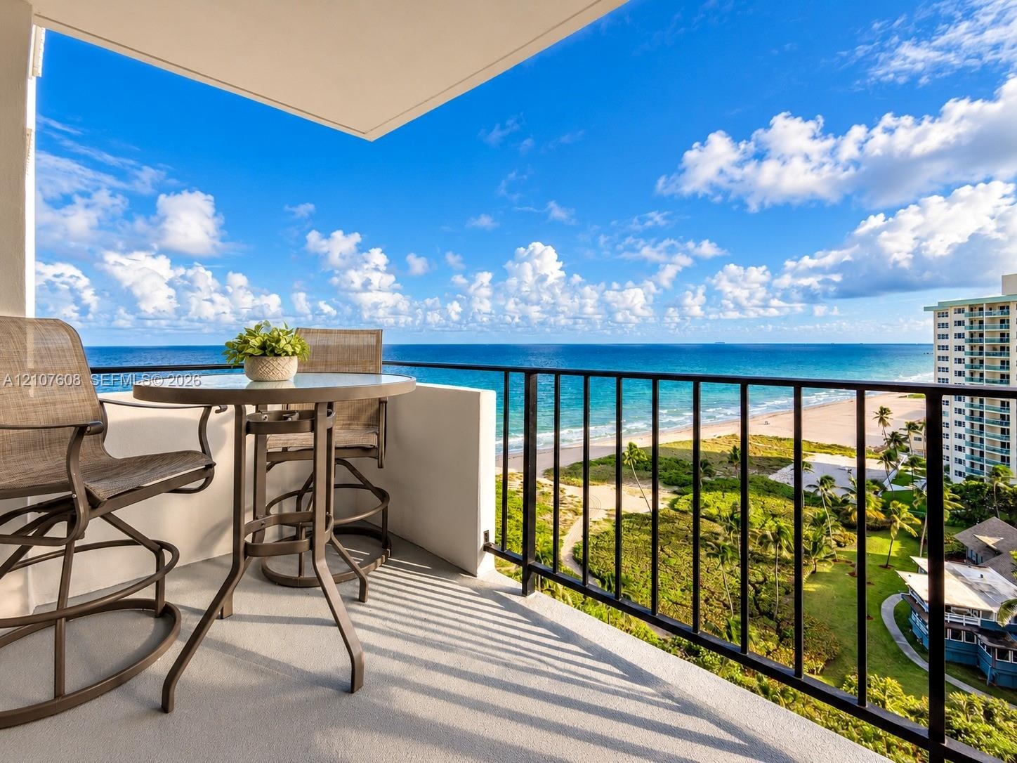 Covered balcony featuring concrete flooring and a metal railing overlooking the coastline and ocean