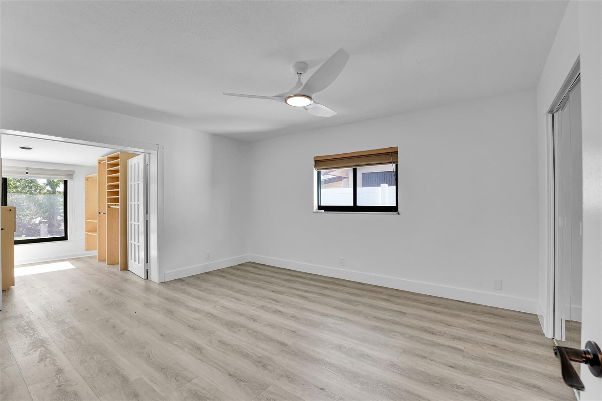 Light wood-finish flooring with white walls and a contemporary ceiling fan