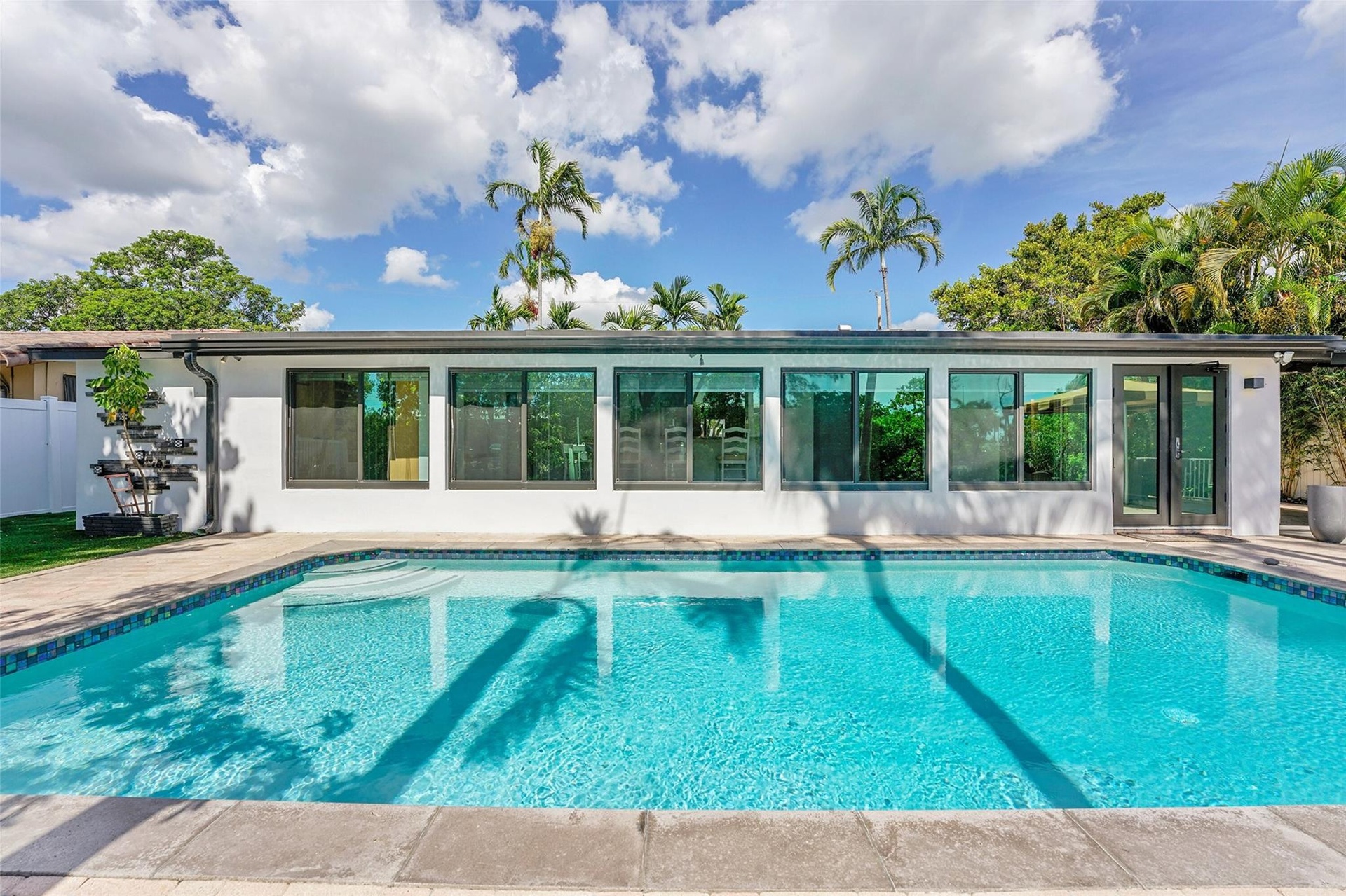 Expansive swimming pool with a tile border, surrounded by a stone paver deck