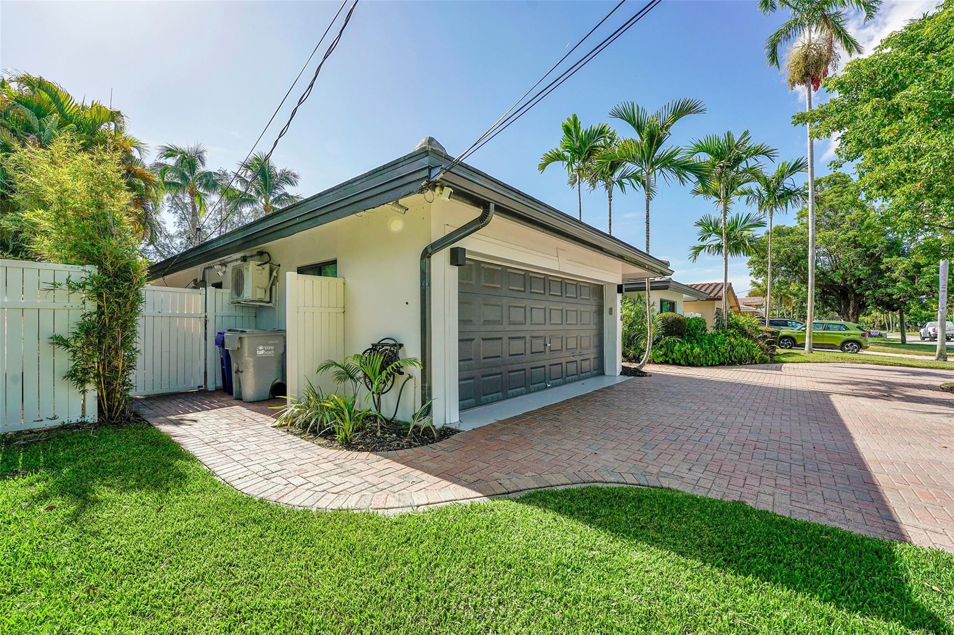 Attached garage with a panel-style door, brick paver driveway, and a manicured lawn