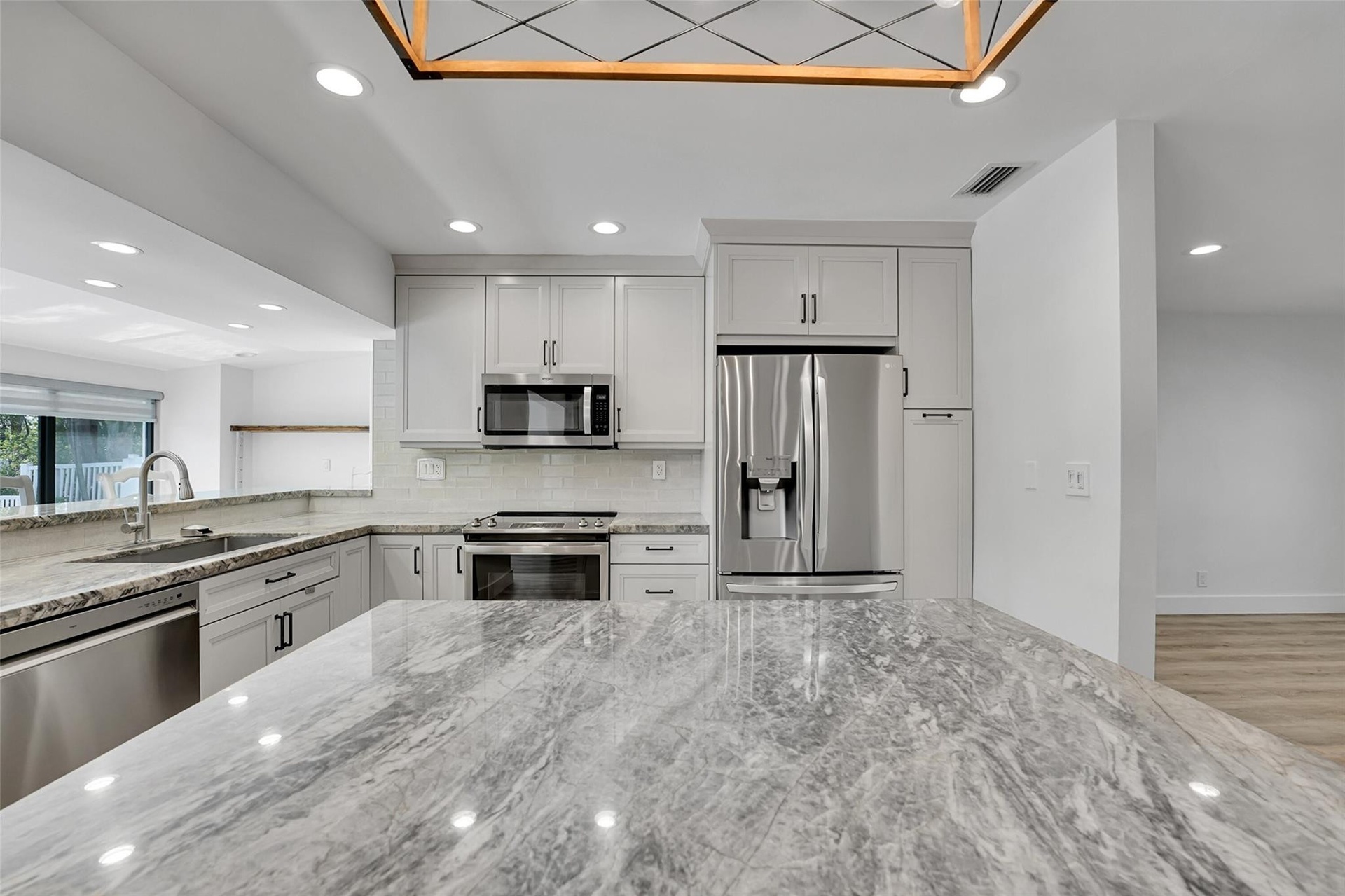 Kitchen featuring light gray cabinetry, stainless steel appliances, a tile backsplash, and stone countertops