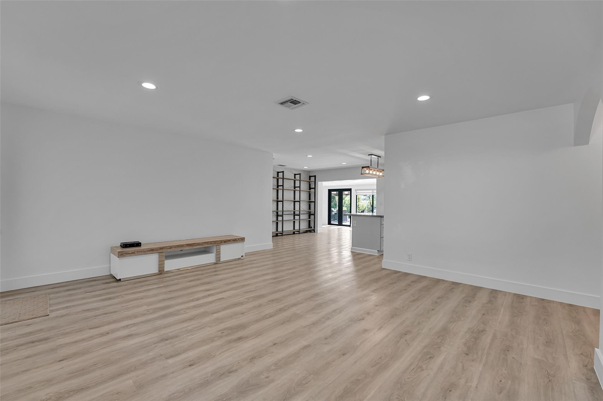 Recessed lighting, light wood-finish flooring, white walls, and a built-in media console