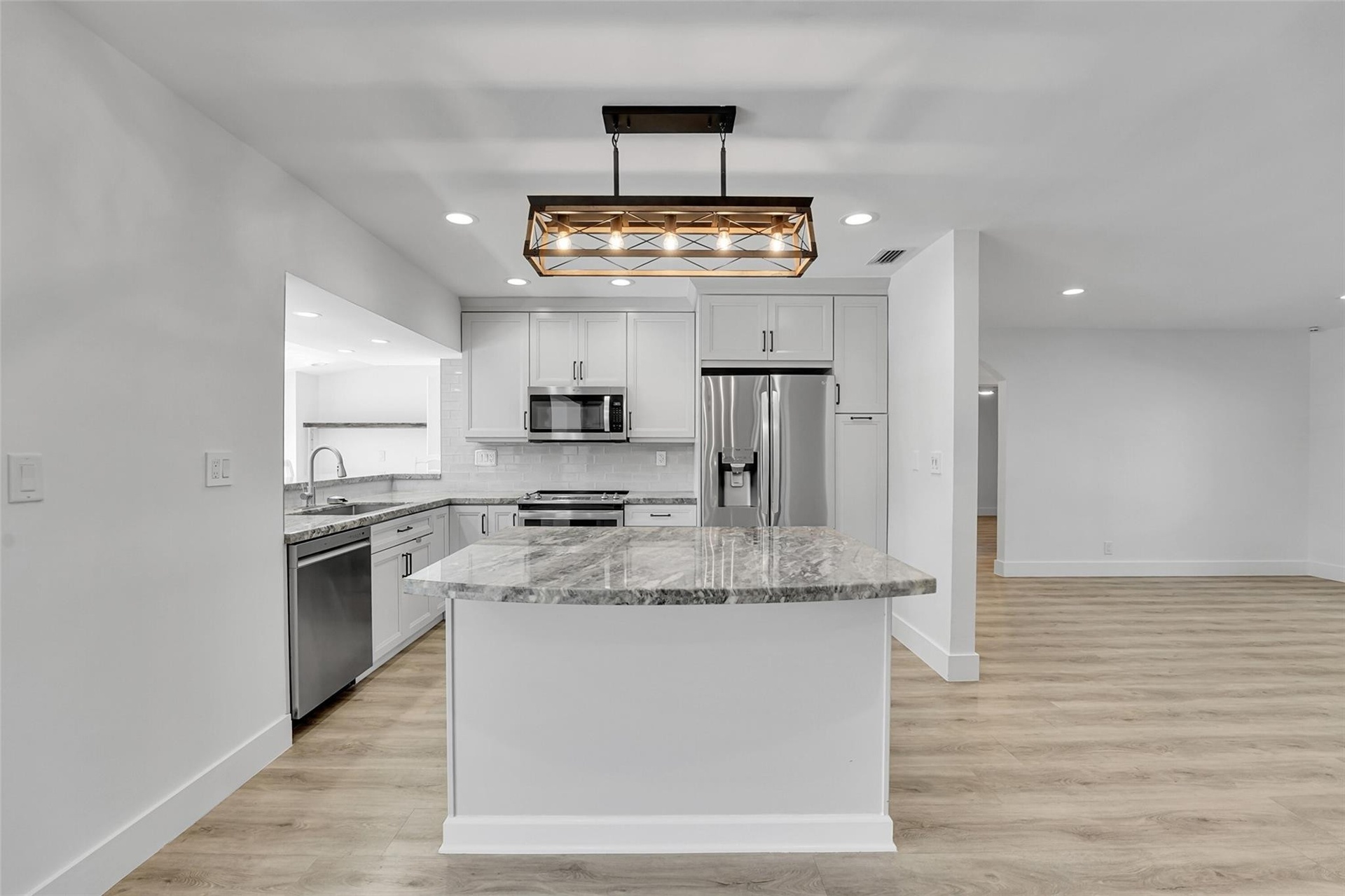 Kitchen featuring a central island with countertop, stainless steel appliances, recessed lighting, and wood-finish flooring