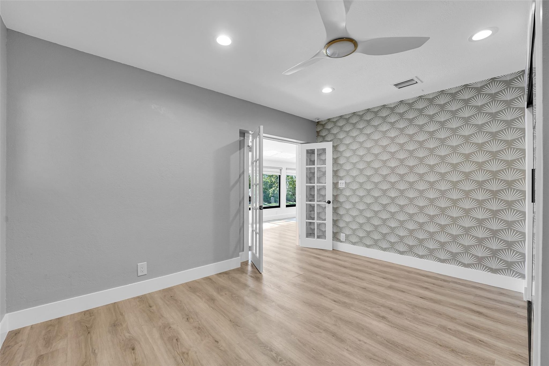 Recessed lighting, wood-finish flooring, accent wall with patterned wallpaper, ceiling fan, and French doors