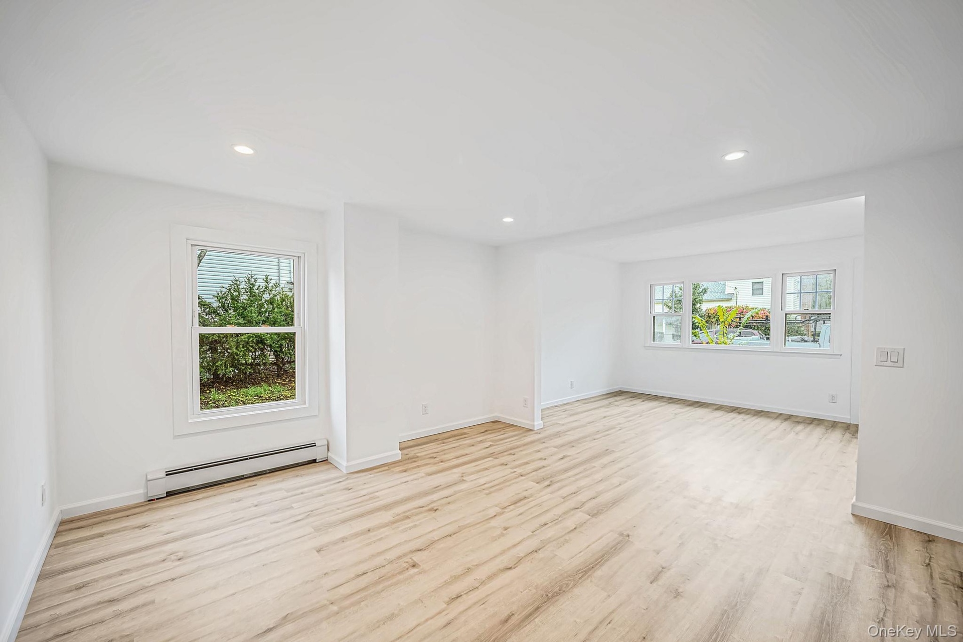 Open-concept interior featuring light wood-finish flooring, recessed lighting, and multiple windows