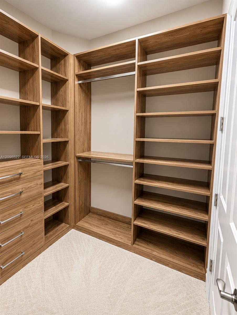 Custom walk-in closet featuring wood-finish cabinetry, built-in shelving, integrated dresser drawers with metal pulls, and dual hanging rods