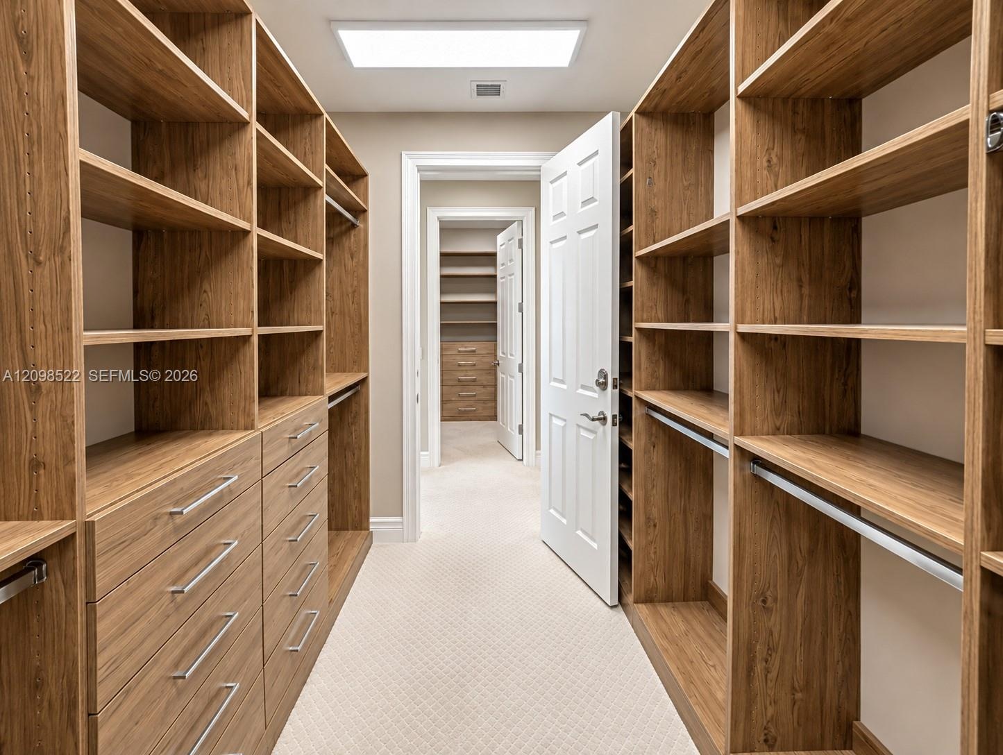 Custom walk-in closet featuring floor-to-ceiling wood-finish cabinetry, built-in shelving, integrated storage drawers, and recessed overhead lighting