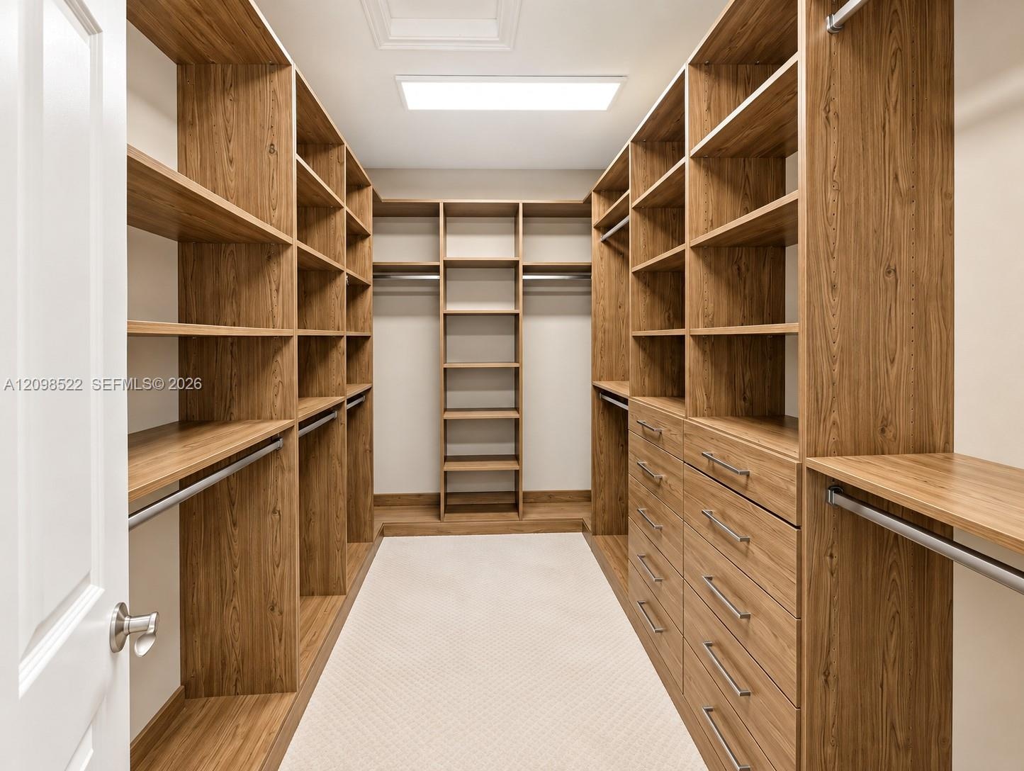 Walk-in closet featuring custom wood-finish built-in shelving, integrated dresser drawers with metallic hardware, multiple garment rods, and recessed 