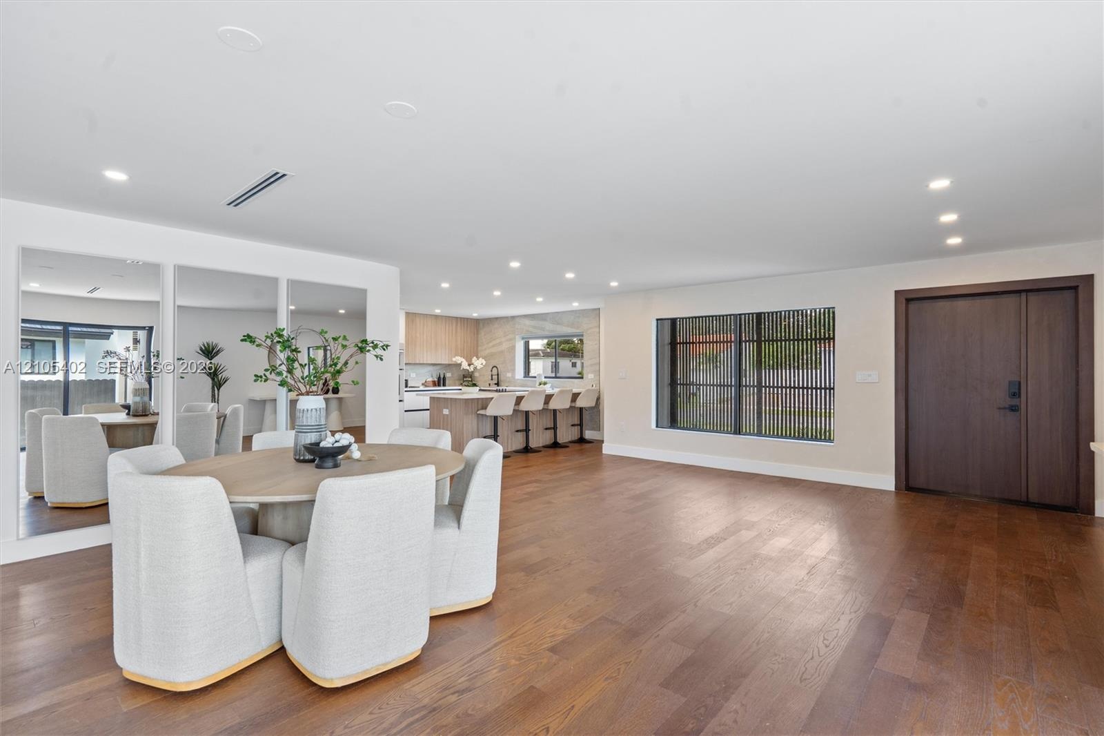 Open-concept interior featuring wood-finish flooring, recessed lighting, a built-in wall mirror, and a solid wood front door