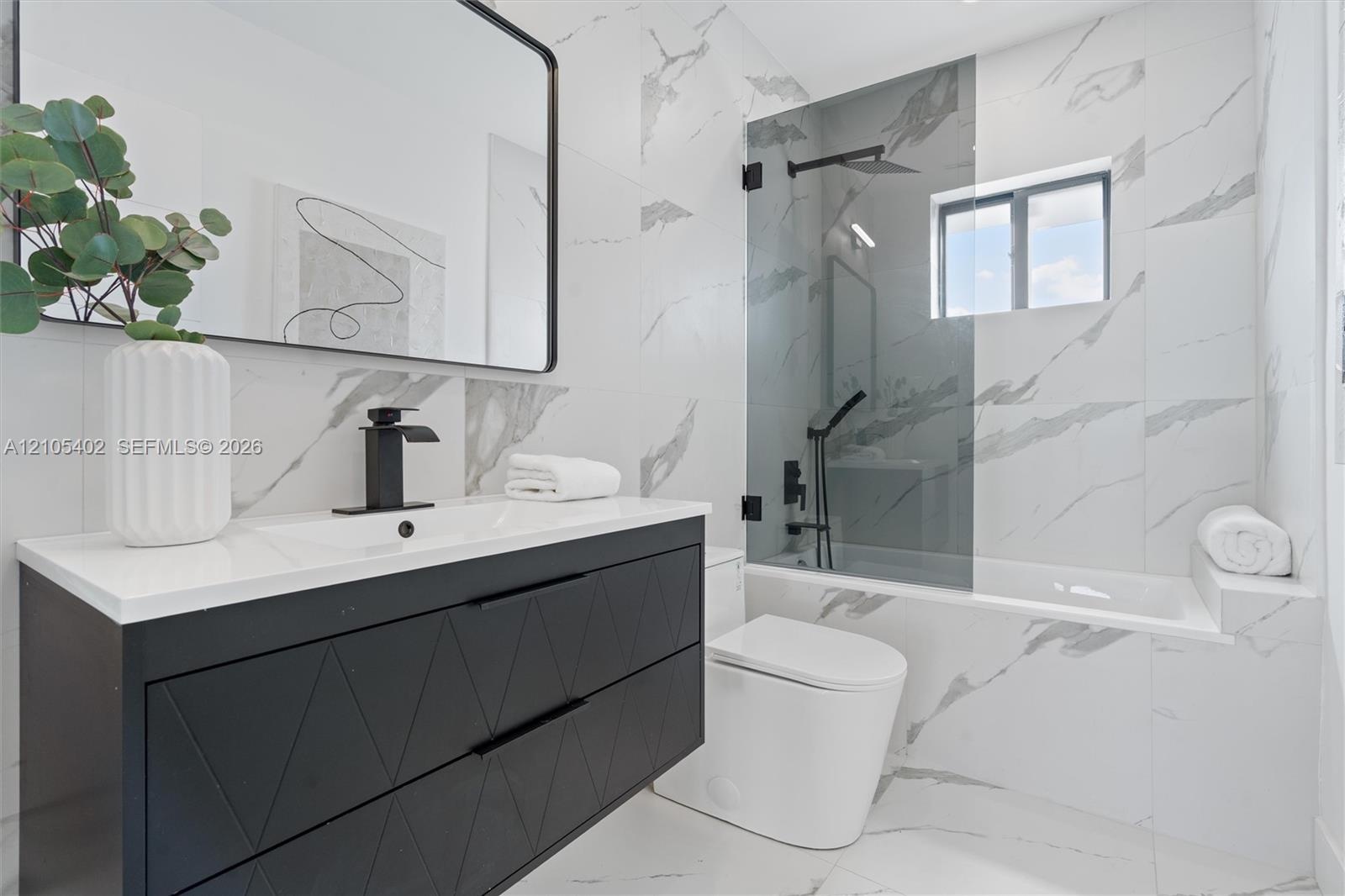 Modern floating vanity with a matte black geometric-patterned finish, white countertop, and black faucet