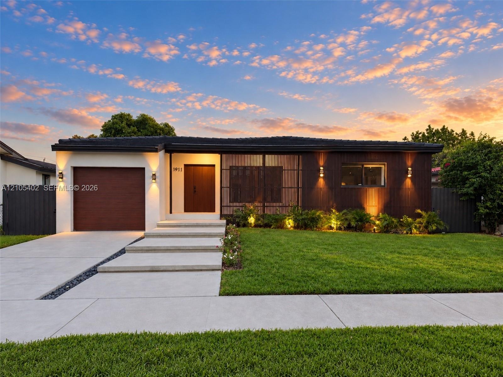 Single-story residence featuring a mid-century modern aesthetic, wood-paneled exterior accents, a concrete driveway with stone drainage detail, a step