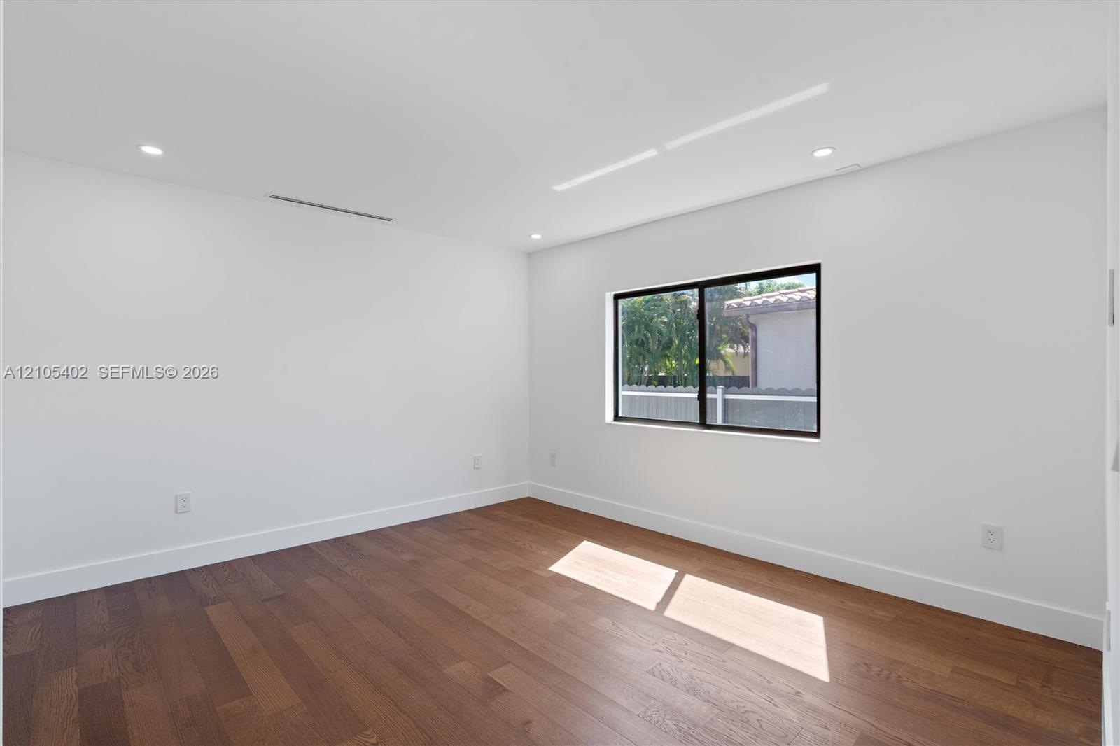 Interior space featuring wood-finish flooring, recessed lighting, and a single-pane window with a black frame