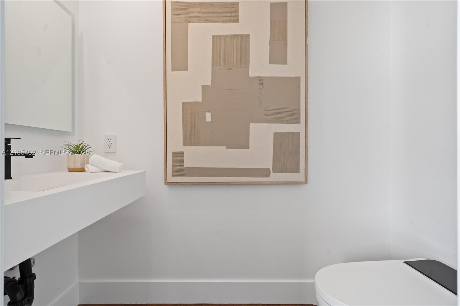 Wall-mounted floating sink with integrated basin, matte black faucet, and modern elongated toilet