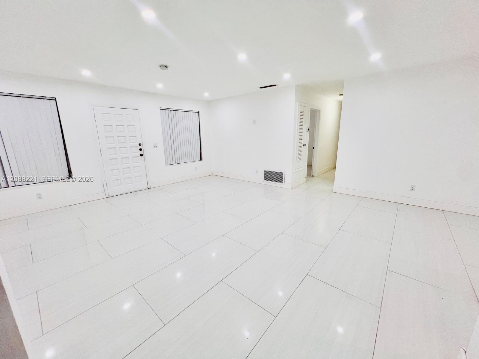Kitchen featuring a central island with a solid surface countertop, white shaker-style cabinetry, stainless steel appliances, and tile flooring