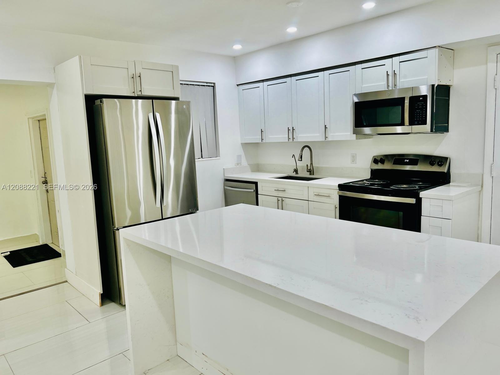 Kitchen featuring white shaker-style cabinetry, quartz countertops, a central island, stainless steel appliances, and recessed lighting