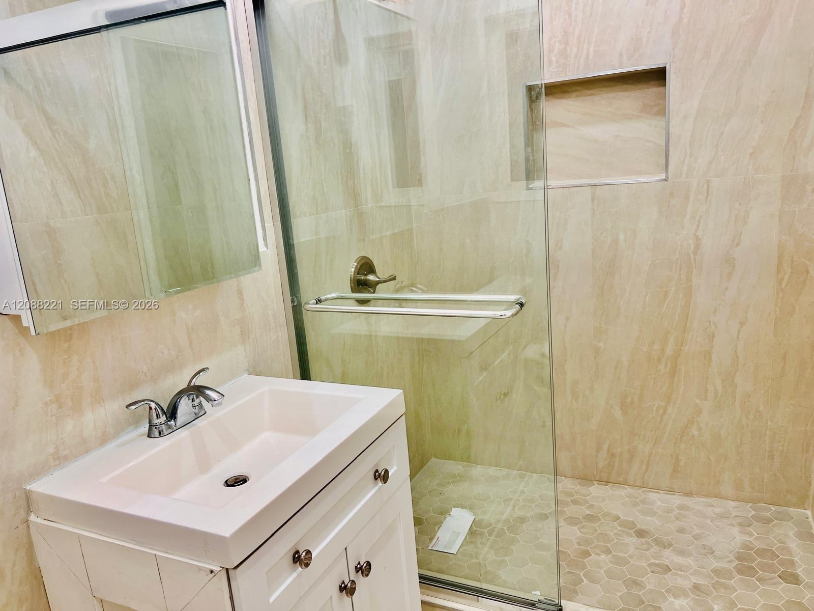Neutral interior featuring large-format ceramic tile flooring, sliding door closet with built-in shelving, and window with vertical blinds
