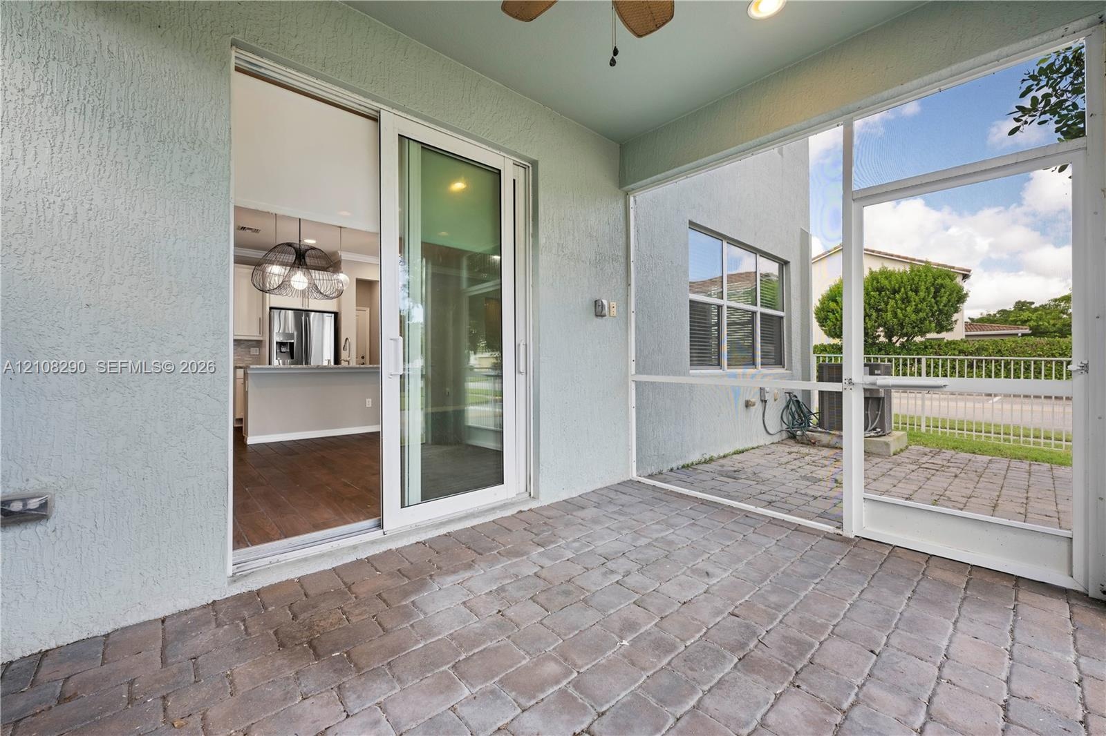 Screened-in patio featuring paver flooring, a ceiling fan, and sliding glass door access to the interior