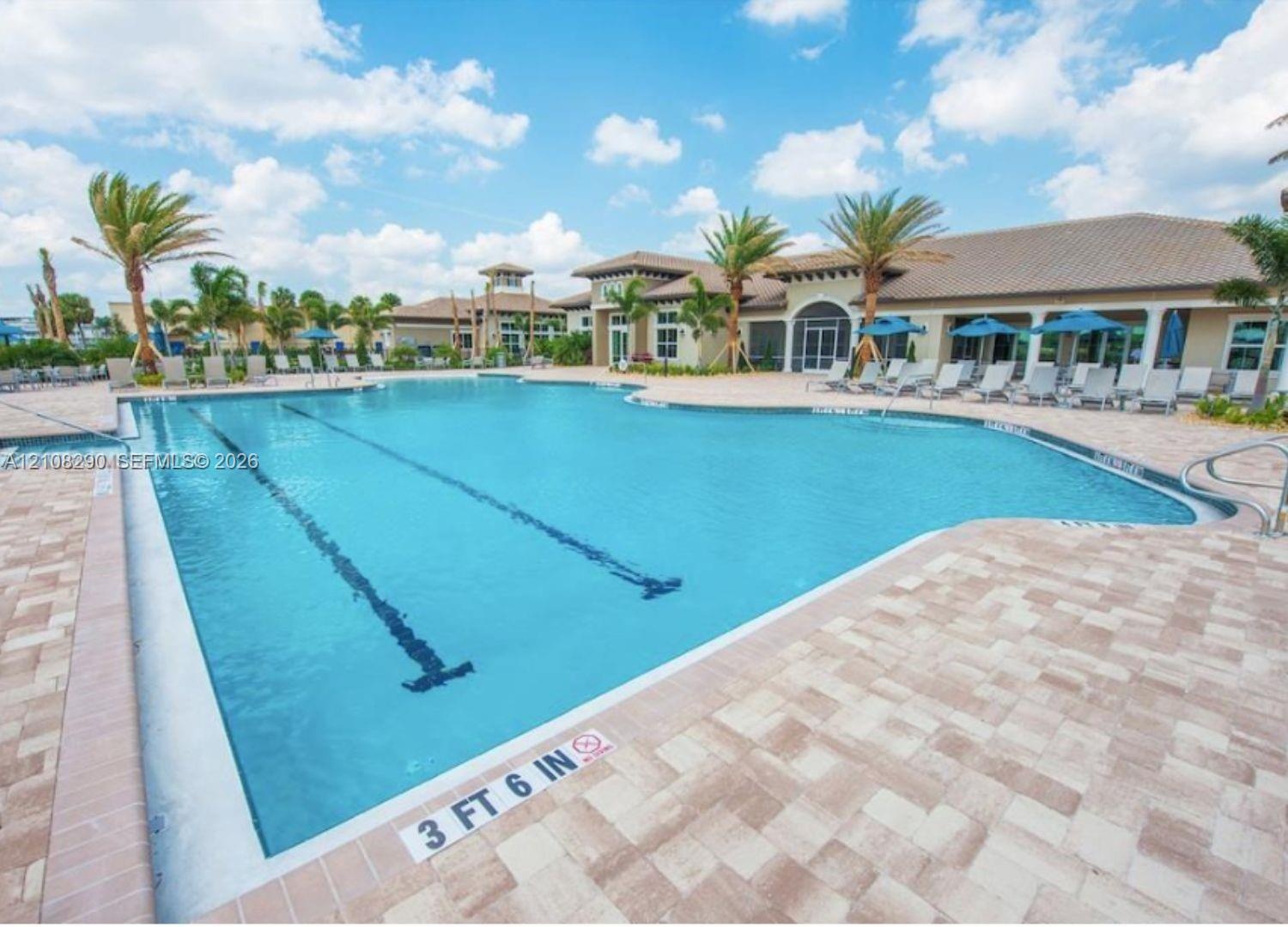 Swimming pool featuring designated lap lanes and a surrounding paved stone deck