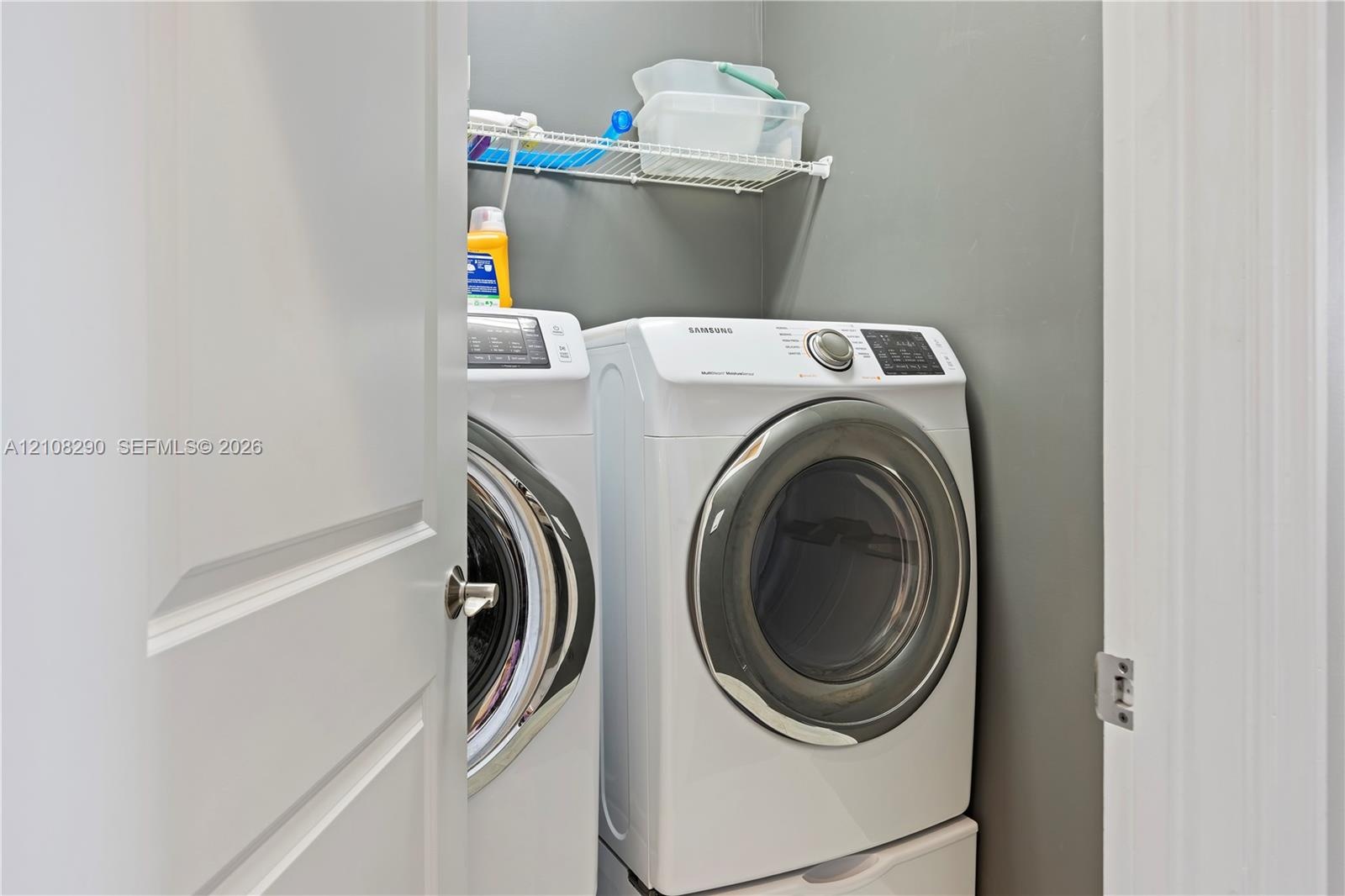 Laundry area featuring a side-by-side washer and dryer set with pedestal bases and a mounted wire shelving unit