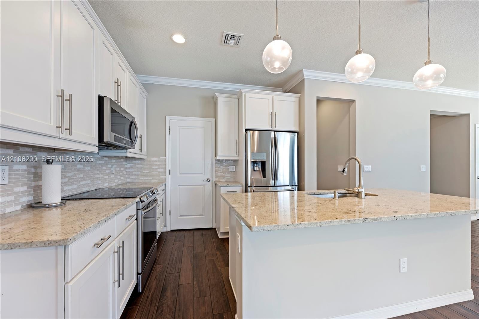 Kitchen featuring white shaker-style cabinetry, stone countertops, stainless steel appliances, decorative glass pendant lighting, and wood-finish floo