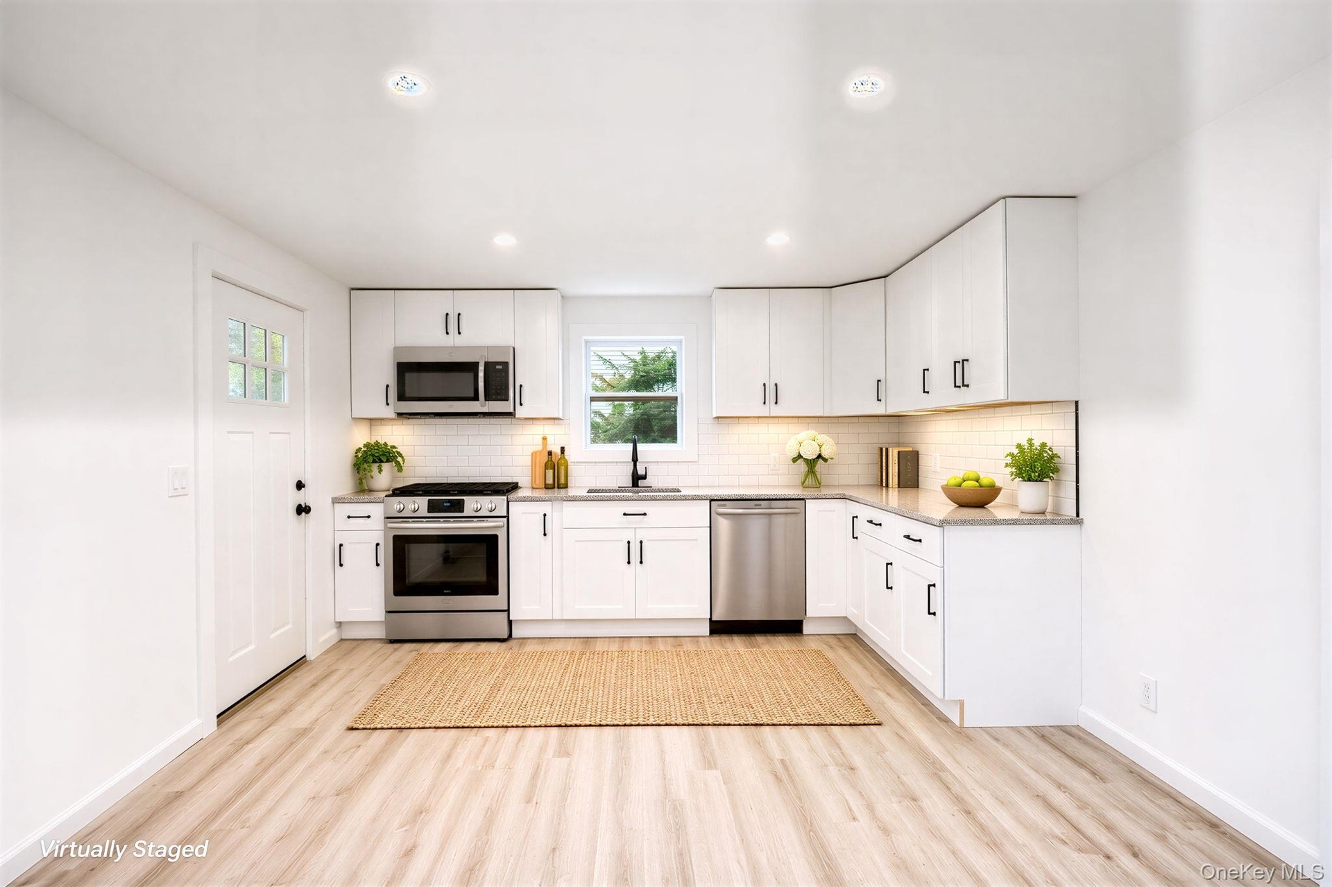 Kitchen featuring white Shaker-style cabinetry, stainless steel appliances, light-toned stone-finish countertops, subway tile backsplash, and vinyl wo
