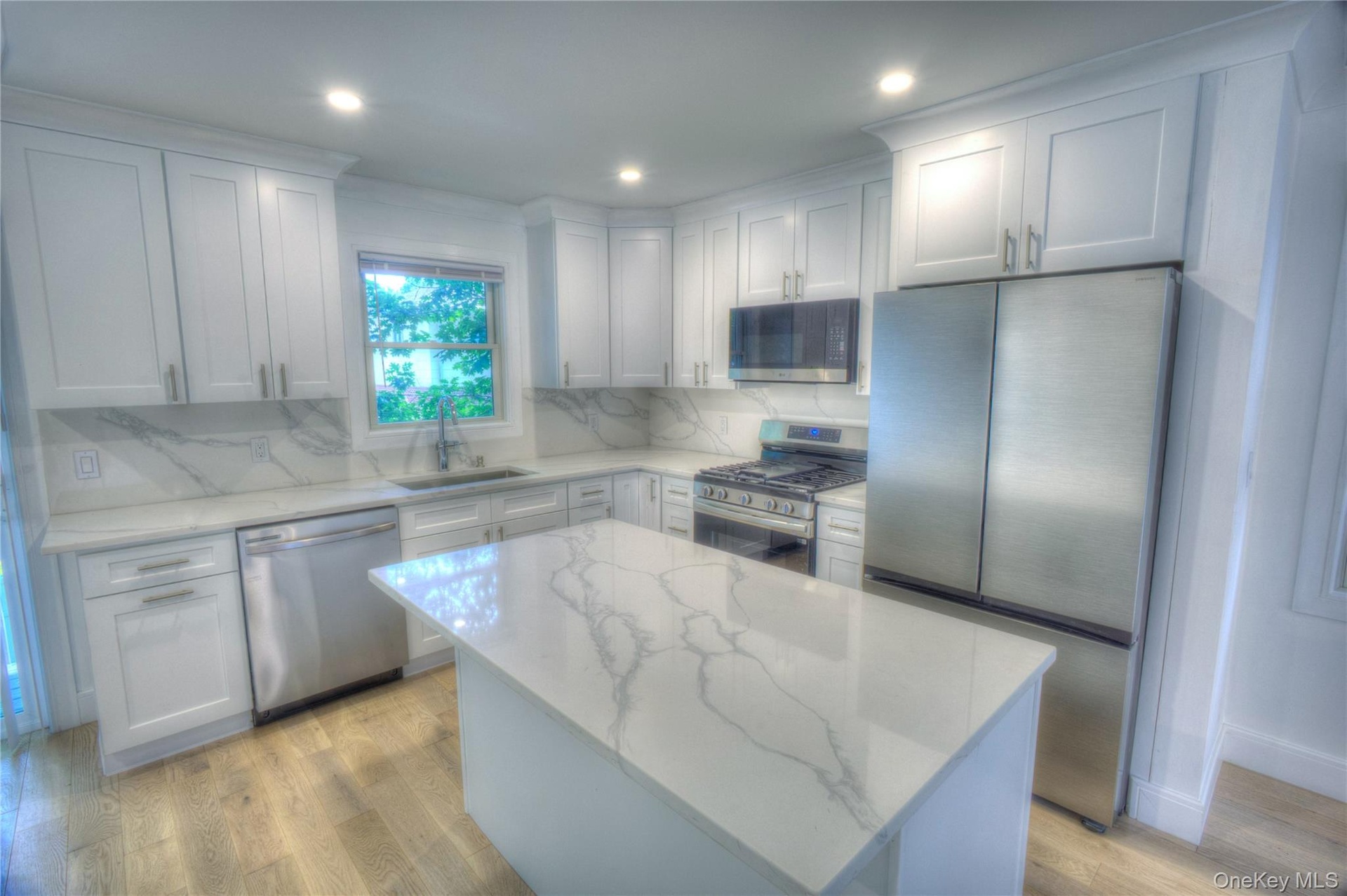 Kitchen featuring white shaker-style cabinetry, stone-patterned countertops, a central island, stainless steel appliances, and wood-finish flooring