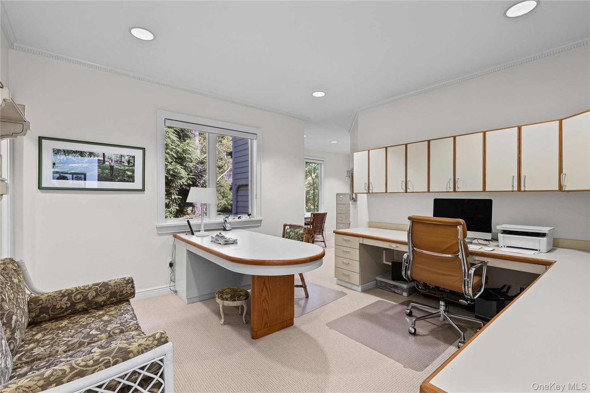 Built-in desk with integrated workspace, custom wall-mounted cabinetry, recessed lighting, and large windows with exterior surroundings. This room cou