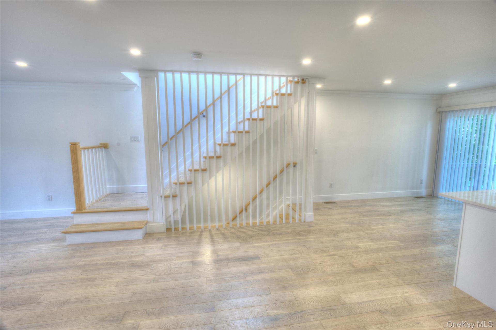 Staircase featuring white vertical spindles, natural wood-finish treads, and recessed lighting throughout