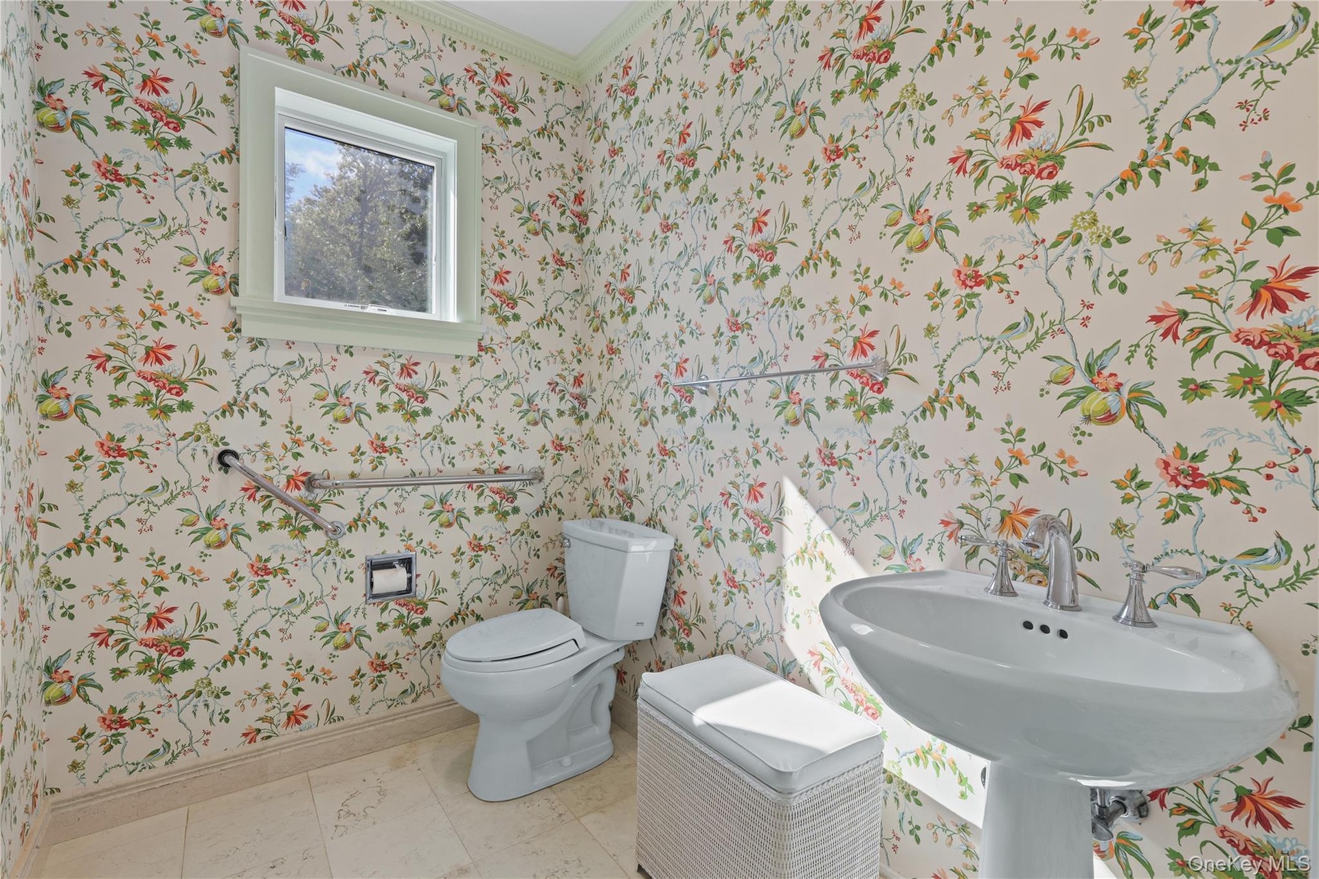 Master Bath featuring floral-patterned wallpaper, pedestal sink with polished chrome hardware, stone-finish tile flooring, and a single-hung window wi