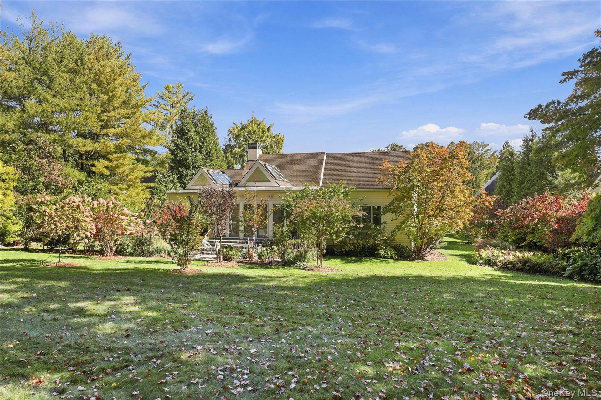 Expansive backyard featuring a lush lawn, mature landscaping, shingle-style roof.